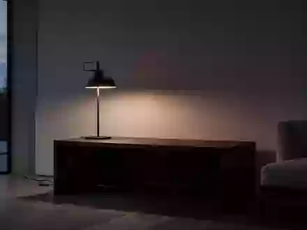 Ein minimalistischer, leerer Wohnraum bei Dämmerlicht mit einem dunklen Holztisch vor einer leeren Wand. - Foto: über boerse-global.de