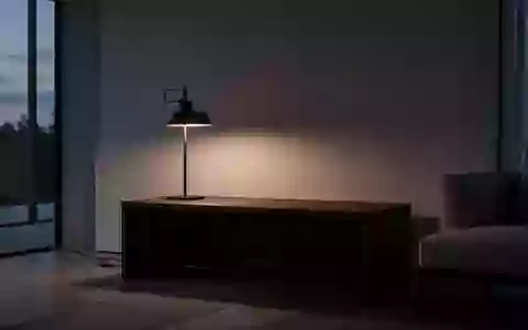 Ein minimalistischer, leerer Wohnraum bei Dämmerlicht mit einem dunklen Holztisch vor einer leeren Wand. - Foto: über boerse-global.de