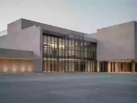 Modernes Verwaltungsgebäude in der Dämmerung mit klarer Architektur und einer leeren Betonfläche im Vordergrund. - Foto: über boerse-global.de