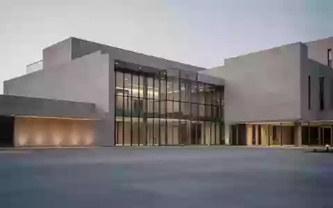 Modernes Verwaltungsgebäude in der Dämmerung mit klarer Architektur und einer leeren Betonfläche im Vordergrund. - Foto: über boerse-global.de