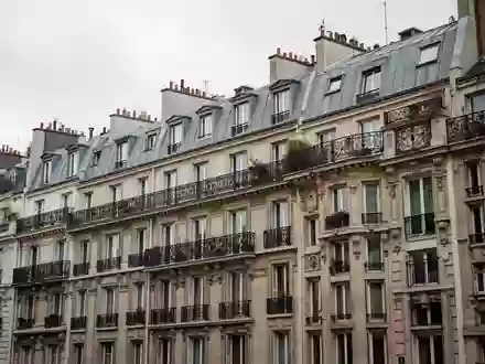 Historische Pariser Wohnfassade mit Balkonen aus Schmiedeeisen unter einem bewölkten Himmel. - Foto: über boerse-global.de