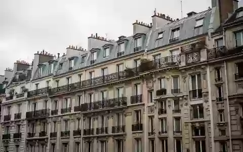 Historische Pariser Wohnfassade mit Balkonen aus Schmiedeeisen unter einem bewölkten Himmel. - Foto: über boerse-global.de