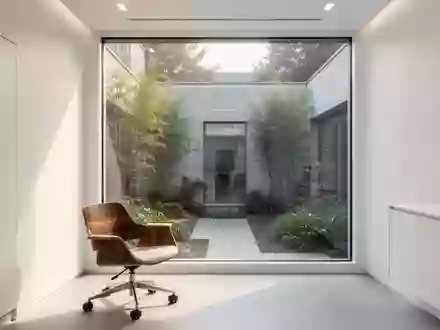 Ein minimalistischer, lichtdurchfluteter Behandlungsraum in einer modernen medizinischen Einrichtung mit Blick in einen Innenhof. - Foto: über boerse-global.de