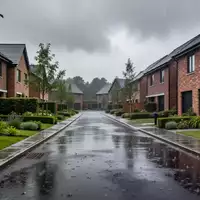 Eine ruhige Wohnstraße nach einem starken Regen mit nassen Straßen und Häuserfassaden unter einem bewölkten Himmel. - Foto: über boerse-global.de