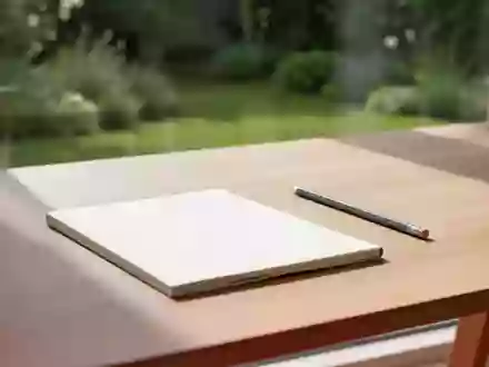 Ein minimalistischer, sonnendurchfluteter Schreibtisch mit einem leeren Notizbuch und einem Stift vor einem Fenster. - Foto: über boerse-global.de