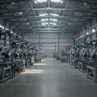 Leere, moderne Industriehalle mit schweren Fertigungsmaschinen und Roboterarmen bei gedimmtem Licht. - Foto: über boerse-global.de