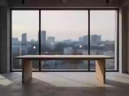 Ein minimalistischer Arbeitsbereich mit einem leeren Holztisch vor einem großen Fenster, das einen urbanen Ausblick bietet. - Foto: über boerse-global.de