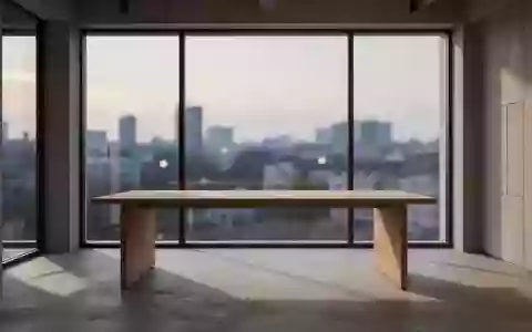 Ein minimalistischer Arbeitsbereich mit einem leeren Holztisch vor einem großen Fenster, das einen urbanen Ausblick bietet. - Foto: über boerse-global.de