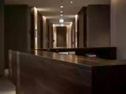 Ein unbesetzter, modern gestalteter Hotelrezeptionsbereich mit dunklem Holz und weicher Beleuchtung. - Foto: über boerse-global.de