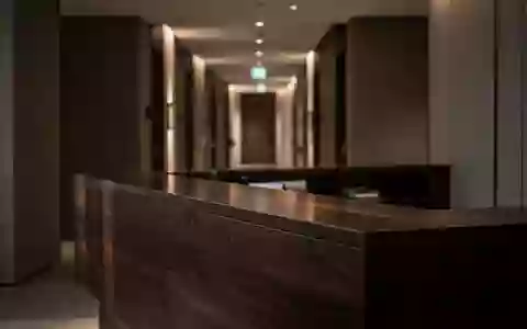 Ein unbesetzter, modern gestalteter Hotelrezeptionsbereich mit dunklem Holz und weicher Beleuchtung. - Foto: über boerse-global.de