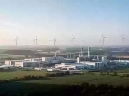Weite Industrielandschaft mit Windkraftanlagen und modernen Produktionsstätten bei Tageslicht - Foto: über boerse-global.de