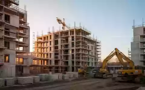 Halbfertiges Wohngebäude auf einer Berliner Baustelle mit Betonstrukturen und Baukränen bei Sonnenuntergang. - Foto: über boerse-global.de