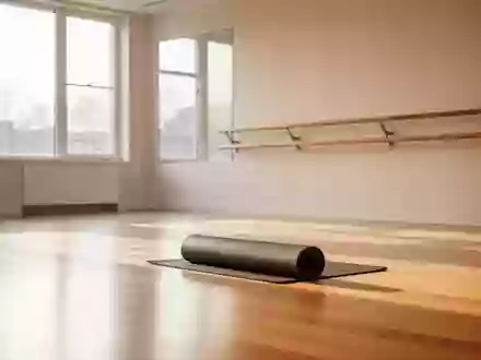Ein heller, minimalistischer Übungsraum mit Holzboden, einer Ballettstange und einer zusammengerollten Yogamatte. - Foto: über boerse-global.de