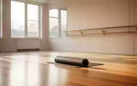 Ein heller, minimalistischer Übungsraum mit Holzboden, einer Ballettstange und einer zusammengerollten Yogamatte. - Foto: über boerse-global.de