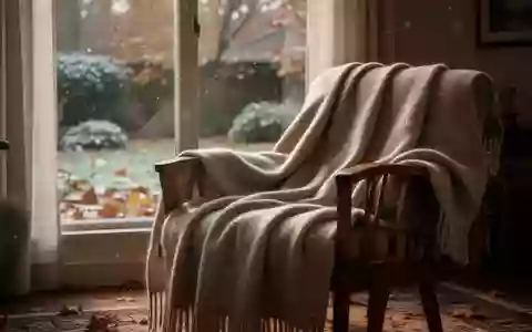 Eine gemütliche, warm beleuchtete Wohnzimmerecke mit einer weichen Wolldecke auf einem Sessel vor einem Fenster an einem Herbsttag. - Foto: über boerse-global.de