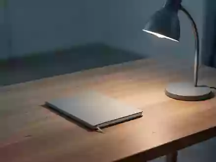 Ein minimalistischer, aufgeräumter Schreibtisch mit einem einzelnen Notizbuch und einer Schreibtischlampe in einem ruhigen Raum. - Foto: über boerse-global.de