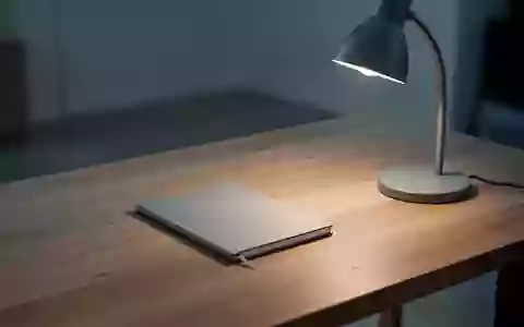 Ein minimalistischer, aufgeräumter Schreibtisch mit einem einzelnen Notizbuch und einer Schreibtischlampe in einem ruhigen Raum. - Foto: über boerse-global.de