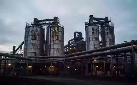 Industrielle Industrieanlage mit großen Metallsilos und Rohrleitungen vor einem bewölkten Abendhimmel. - Foto: über boerse-global.de