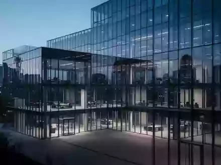 Ein modernes, minimalistisches Bürogebäude aus Glas in der Dämmerung, das die Lichter der Stadt reflektiert. - Foto: über boerse-global.de