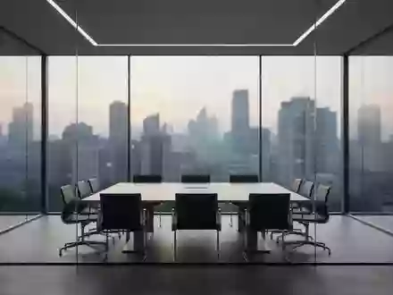 Ein minimalistischer Konferenzraum mit Glaswänden und Blick auf eine Stadt bei Dämmerung. - Foto: über boerse-global.de
