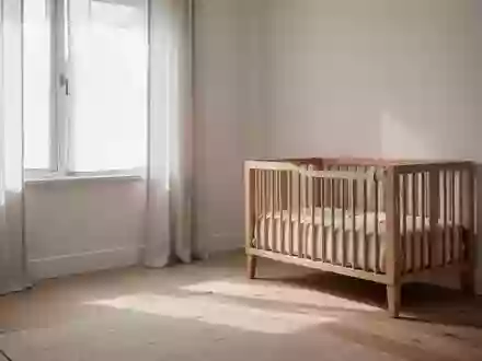 Ein helles, minimalistisch eingerichtetes Kinderzimmer mit sanftem Tageslicht, Holzmöbeln und hellem Holzboden. - Foto: über boerse-global.de