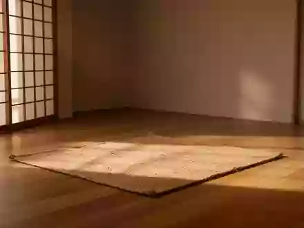 Ein minimalistischer Meditationsraum mit einer schlichten Matte auf einem Holzboden in hellem, natürlichem Licht. - Foto: über boerse-global.de