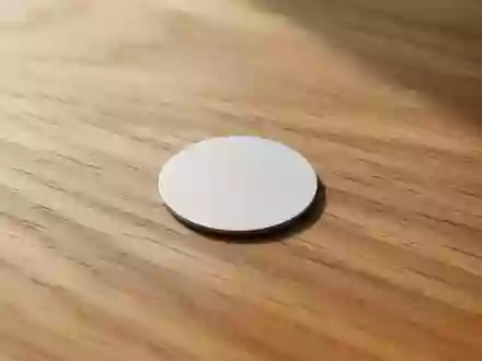 Ein einzelner NFC-Tag liegt auf einer strukturierten Holzoberfläche in natürlichem Licht. - Foto: über boerse-global.de