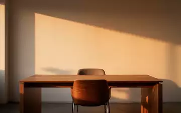 Ein minimalistischer, ruhiger Büroarbeitsplatz mit leerem Stuhl in warmem Licht, der eine Atmosphäre von Besonnenheit ausstrahlt. - Foto: über boerse-global.de