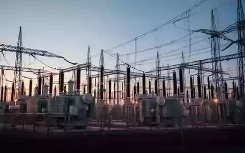 Eine weitläufige elektrische Umspannstation mit Hochspannungstransformatoren und Stromleitungen in der Abenddämmerung. - Foto: über boerse-global.de