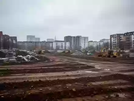 Eine leere Baustelle in einem Hamburger Stadtgebiet mit aufgeschütteter Erde und Baumaterialien vor einer Häuserzeile. - Foto: über boerse-global.de