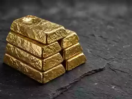 Goldbarren auf einer dunklen Schieferplatte bei gedimmter, cinematischer Beleuchtung. - Foto: über boerse-global.de