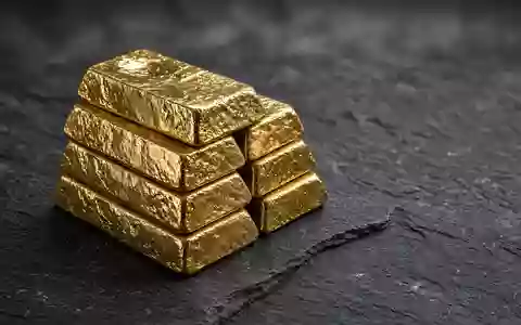 Goldbarren auf einer dunklen Schieferplatte bei gedimmter, cinematischer Beleuchtung. - Foto: ĂĽber boerse-global.de