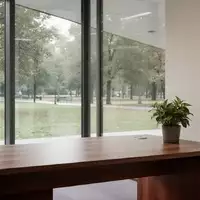 Ein minimalistisches, leeres Büro mit einem Schreibtisch und einer Pflanze vor einem Fenster mit Blick ins Grüne. - Foto: über boerse-global.de