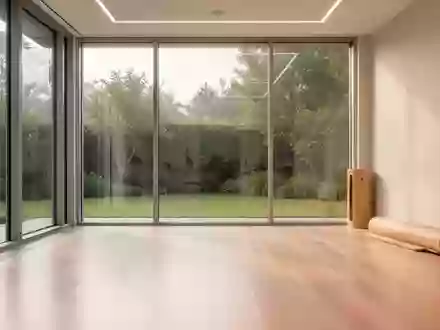 Ein heller, minimalistischer Therapieraum in einer Rehabilitationsklinik mit großen Fenstern und Blick in einen Garten. - Foto: über boerse-global.de