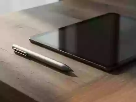 Ein digitaler Eingabestift liegt auf einem hölzernen Schreibtisch neben einem ausgeschalteten Tablet-Display. - Foto: über boerse-global.de