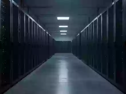 Dunkler, weitläufiger Serverraum mit leeren Serverschränken in einer minimalistischen Industrieumgebung. - Foto: über boerse-global.de