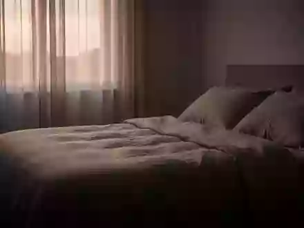 Ein ruhiges, minimalistisches Schlafzimmer in der Morgendämmerung mit weichem Licht und ungemachten Bettlaken. - Foto: über boerse-global.de