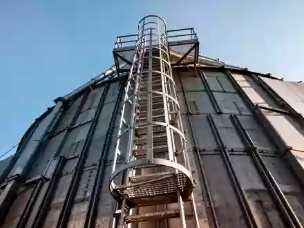 Metallene Aufstiegsleiter mit Rückenschutz an einem hohen landwirtschaftlichen Silo aus Beton. - Foto: über boerse-global.de