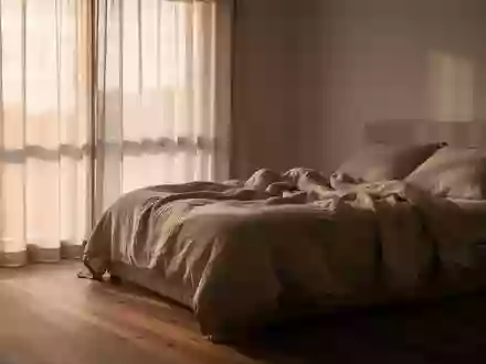 Ein minimalistisch eingerichtetes Schlafzimmer bei Tagesanbruch mit sanftem, natürlichem Licht und neutraler Bettwäsche. - Foto: über boerse-global.de