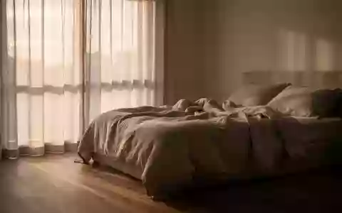 Ein minimalistisch eingerichtetes Schlafzimmer bei Tagesanbruch mit sanftem, natürlichem Licht und neutraler Bettwäsche. - Foto: über boerse-global.de