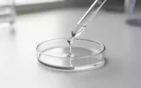 Eine Laborpipette gibt eine Flüssigkeit in eine Petrischale auf einem sauberen, weißen Labortisch. - Foto: über boerse-global.de