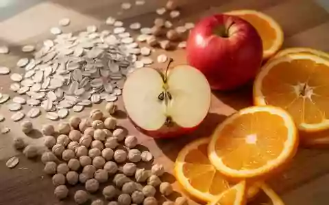 Frische Haferflocken, Kichererbsen, Äpfel und Zitrusfrüchte auf einer hölzernen Arbeitsfläche als Symbol für herzgesunde Ernährung. - Foto: über boerse-global.de