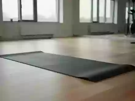 Eine saubere, minimalistische Trainingsumgebung mit einer einzelnen Yogamatte auf einem hellen Holzboden in einem lichtdurchfluteten Raum. - Foto: über boerse-global.de