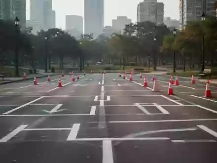 Ein leerer, mit Pylonen markierter Verkehrsübungsplatz auf Asphalt in einem Park bei Tageslicht. - Foto: über boerse-global.de
