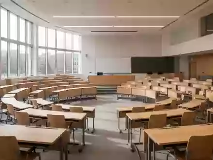 Ein moderner, leerer Seminarraum an einer Universität mit kreisförmig angeordneten Tischen und Stühlen bei Tageslicht. - Foto: über boerse-global.de