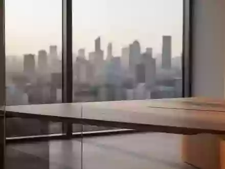Ein minimalistischer Arbeitsbereich mit einem leeren Holztisch vor einem großen Fenster mit Blick auf eine Skyline. - Foto: über boerse-global.de
