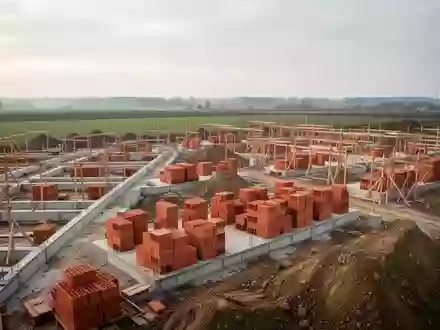 Baustelle eines neuen Wohnquartiers mit Erdarbeiten und Fundamenten auf einem weitläufigen Gelände unter bewölktem Himmel. - Foto: über boerse-global.de