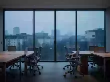 Ein minimalistisches, ruhiges Büro bei Dämmerung mit leeren Schreibtischen und Blick auf eine verschwommene Stadtlandschaft. - Foto: über boerse-global.de