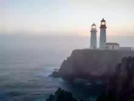 Ein Leuchtturm auf einer nebligen Klippe über dem Ozean als Symbol für Stabilität und Unterstützung. - Foto: über boerse-global.de