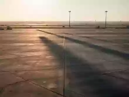 Leeres Rollfeld eines Flughafens während der Abenddämmerung mit langen Schatten auf dem Betonboden. - Foto: über boerse-global.de